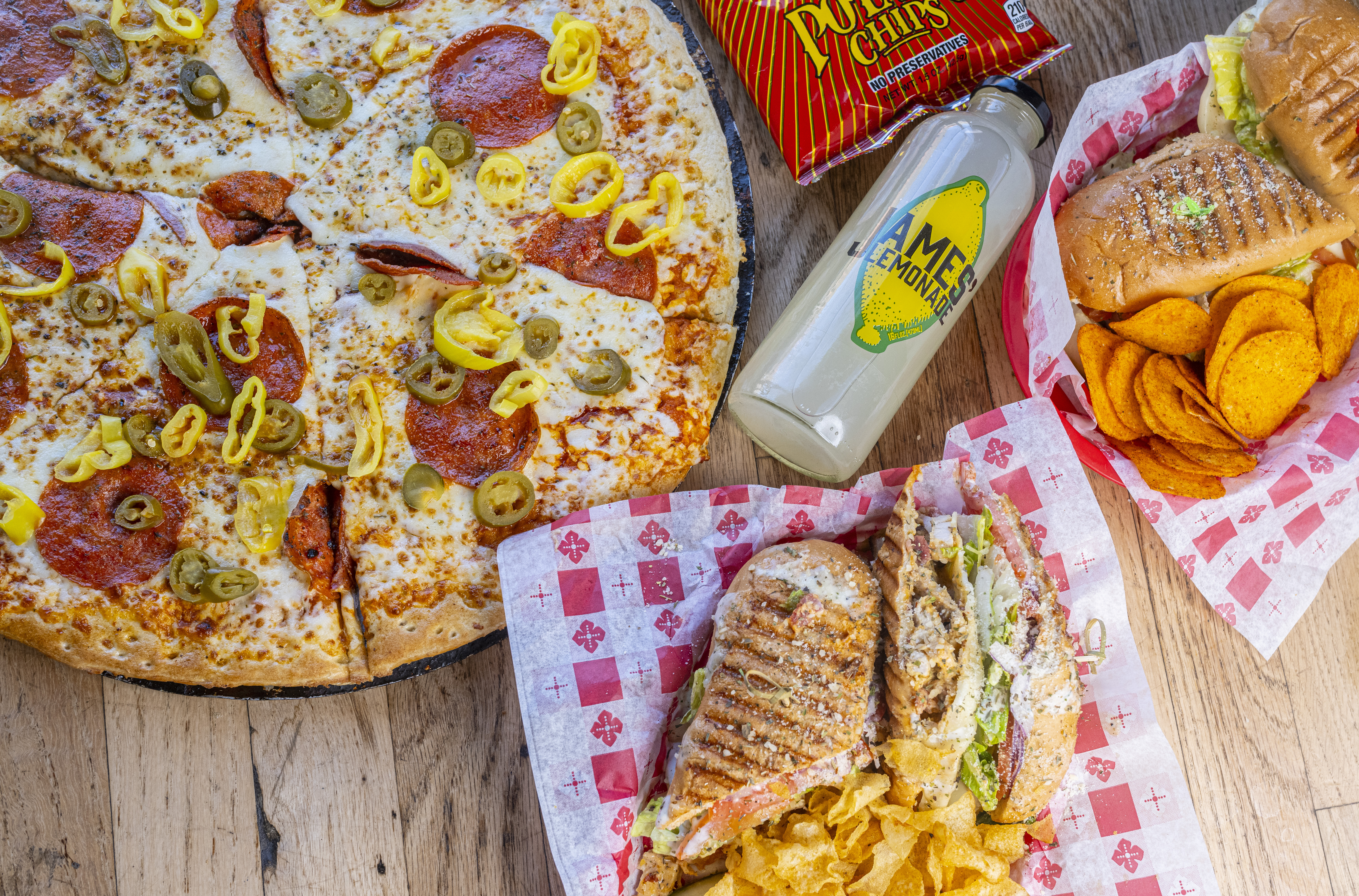 Guy’s pizza, sandwiches, chips and lemonade spread across a table