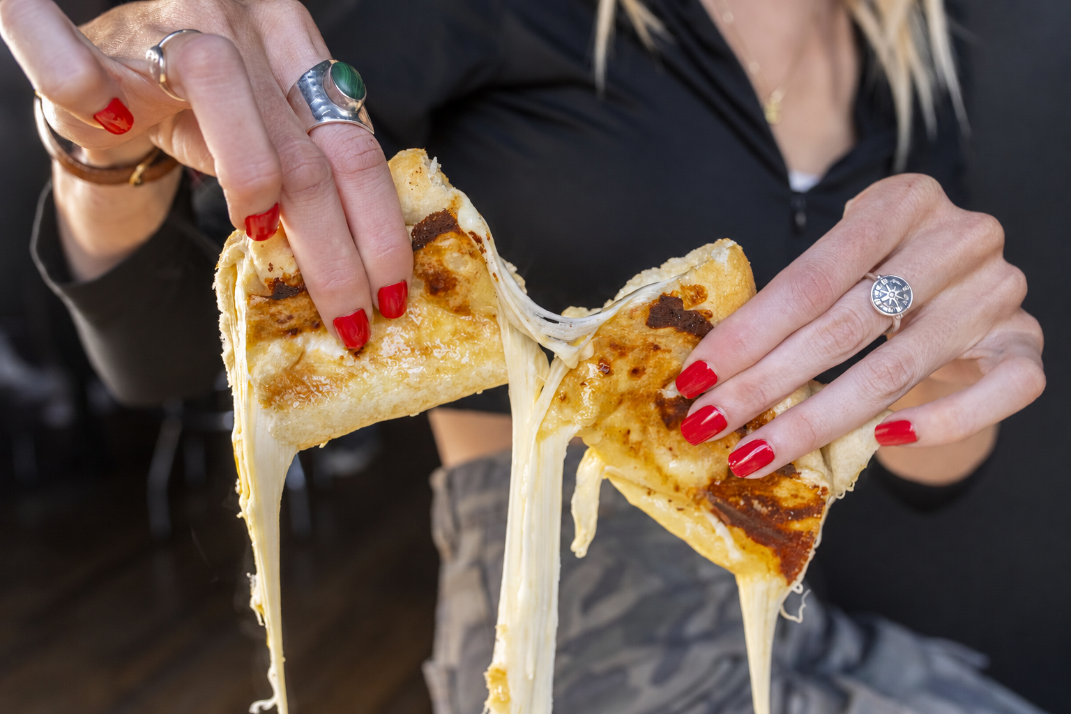 A pizza bone pulled apart with a long stretch of melted cheese